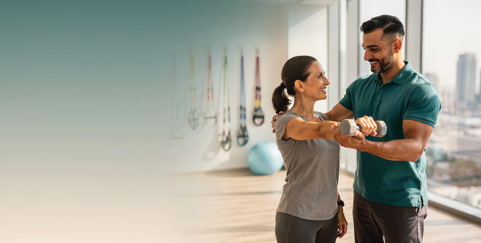 A physiotherapist guiding a smiling woman through a light shoulder exercise