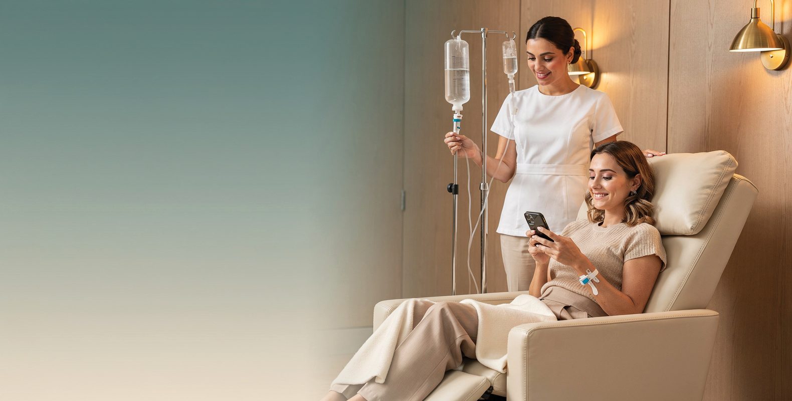 A relaxed woman in a wellness lounge chair during an IV drip, a nurse beside her